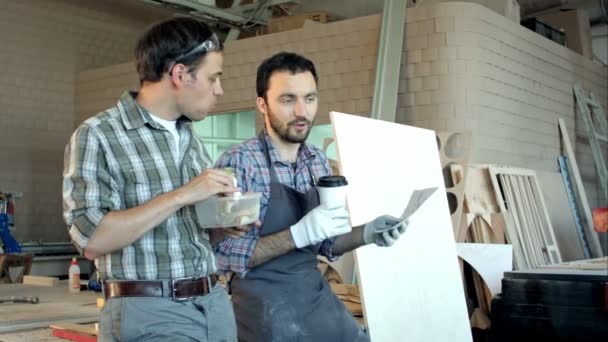 Dos carpinteros discutiendo el trabajo y uno de ellos comiendo . — Vídeos de Stock