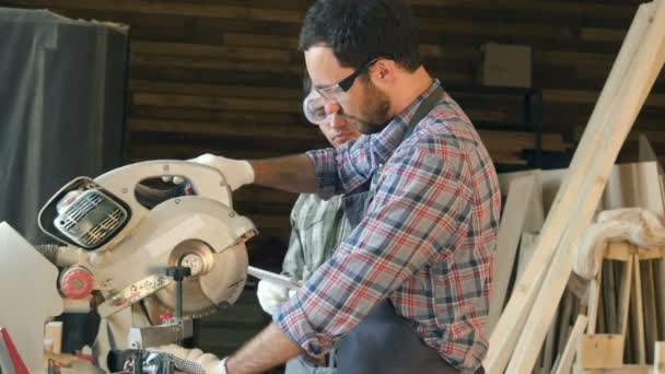 Carpinteiro mostra estudante como trabalhar com serra elétrica — Vídeo de Stock
