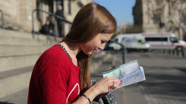 Жінка на сходах бачить туристичну карту, яка дивиться навколо трафіку позаду — стокове відео