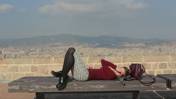 Mujer relajada yacía en la cima del banco de la ciudad — Vídeos de Stock