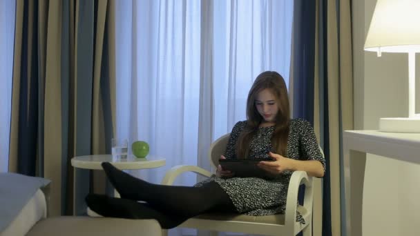Žena v šatech hledání na internetu digitálním tabletu v hotelovém pokoji — Stock video