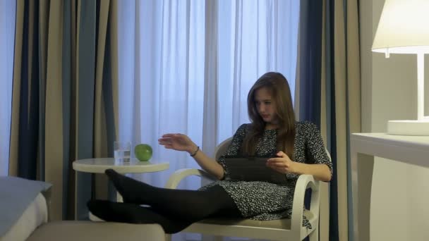 Female use tablet in hotel room and drink water from glass — Stock Video