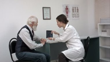 Kadın doktor ofisi üst düzey hastayla konuşuyor ve onu tablet MRG ile gösterilen.