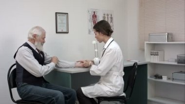 Yaşlı hasta nabız ölçme doktor tarafından görülmektedir.