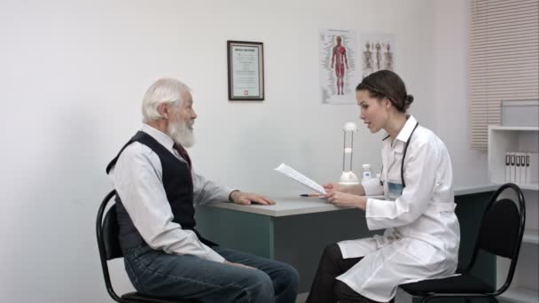 Zufriedener Arzt und Patient diskutieren in Klinik über Berichte. — Stockvideo