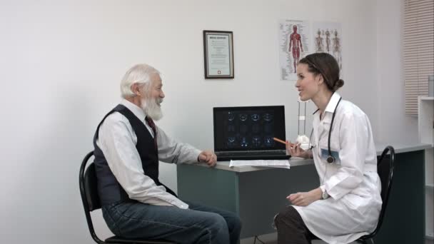 Médecin montrant IRM sur ordinateur portable et disant de bonnes nouvelles au patient âgé . — Video
