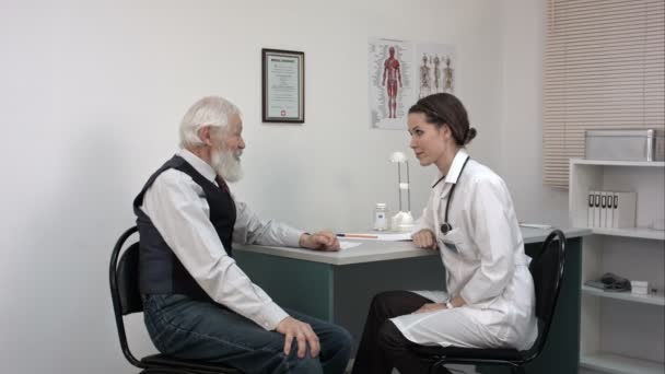 Young female doctor showing showing patient an international certificate. — Stock Video