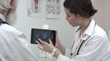 Doktor hastaya tablet üzerinde beyin taramaları hakkında konuşmak.
