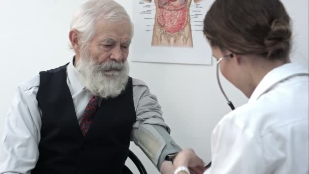 Doctor measuring blood pressure of male patient. — Stock Video