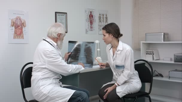 Lekarz tłumacząc RTG płuc lekarka w gabinecie lekarskim. — Wideo stockowe