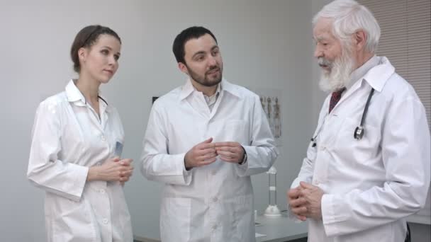 Schnelles Treffen. Drei selbstbewusste Ärzte diskutieren etwas. — Stockvideo