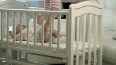 Anne bir karyolası uyuyan sevimli bebek kızı okşama