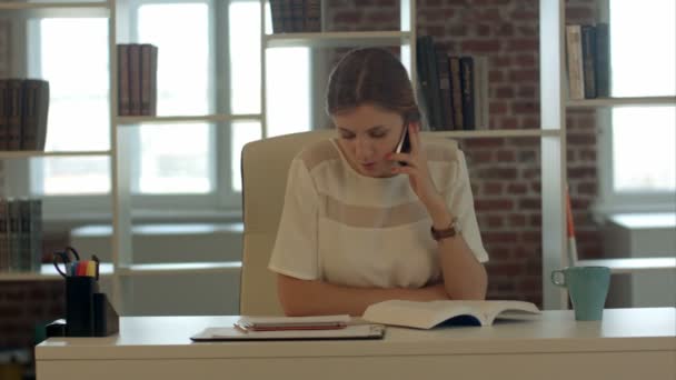 Vacker ung blond kvinna tala i mobiltelefon och läser bok — Stockvideo