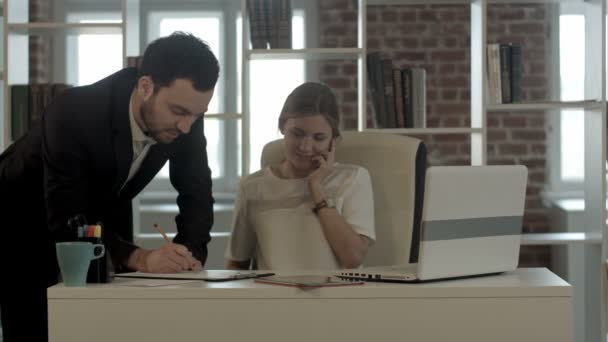 Porträtt av en kvinna att göra ett telefonsamtal medan hennes kollega arbetar på ett kontor — Stockvideo