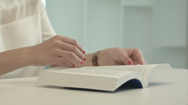 Frau sitzt am Tisch und liest Buch — Stockvideo