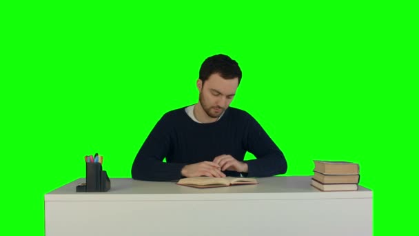 Un hombre joven leyendo un libro en el ordenador portátil en una pantalla verde, Chroma Key — Vídeos de Stock