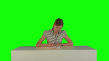 Young girl sitting in classroom at lecture and listening teacher on a Green Screen