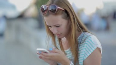 kız ciddi bir şehir seti oturan bir akıllı telefon kullanarak