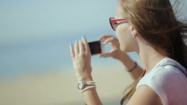 Young beatiful woman travel, sightseeing in tourist bus - happy teenage girl in sunglasses taking picture by smart phone