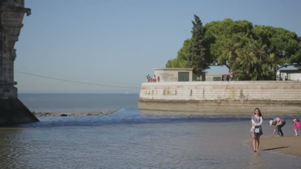 Lisboa, Portugal - Septiembre 2015: Mujer joven en vestido caminando sin zapatos en el agua en el puerto frente al océano — Vídeo de stock