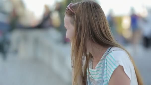 Щаслива дівчина розмовляє по смартфону в міській набережній сидить — стокове відео