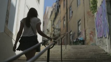 young woman goes up by ledder on street of Lisbon