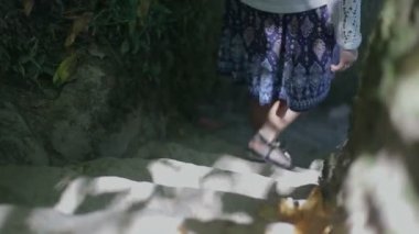 Yeşil parkta merdivenin taş basamaklarında mavi ayakkabılı kadın bacakları, aşağı gidiyor