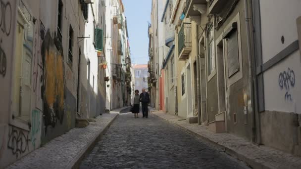 Lisszabon, Portugália-szeptember 2015: a régi pár séta gondolta a lisszaboni utcán együtt egy régi utcán — Stock videók