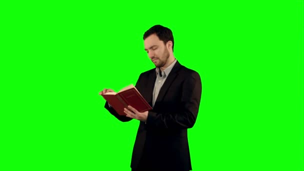 Universitetsstudent med bok om laptop på en grön skärm, Chroma Key. — Stockvideo