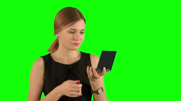 Mujer con maquillaje de lápiz labial mirándose en el espejo en una pantalla verde — Vídeo de stock