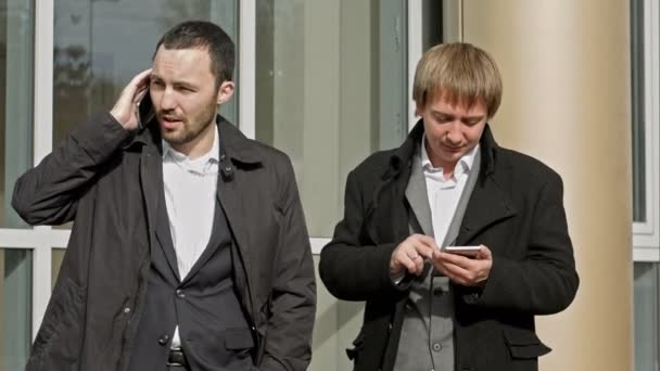 Due uomini d'affari che parlano sul cellulare e leggono messaggi — Video Stock