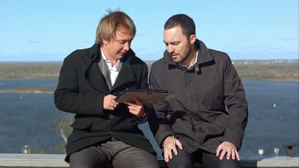 A divertir-me. Dois homens com tablet sentado no banco — Vídeo de Stock
