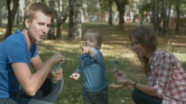 Mutlu anne, baba ve oğul kabarcıklar parkta üfleme.