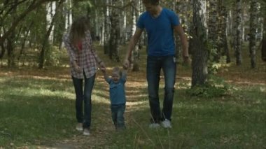 Mutlu genç aile güneşli bir gün açık havada sonbahar parkında eğlenceli yaşıyor. Anne, babam ve küçük çocuk parkta koşup.