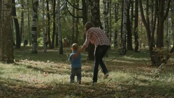 母亲带着儿子在秋天户外散步. — 图库视频影像