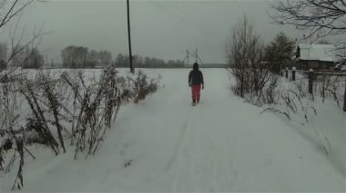 Rusya'nın kırsal kesimlerinde kış yolu ile karlı alanda yürüyen adamın havadan görünümü