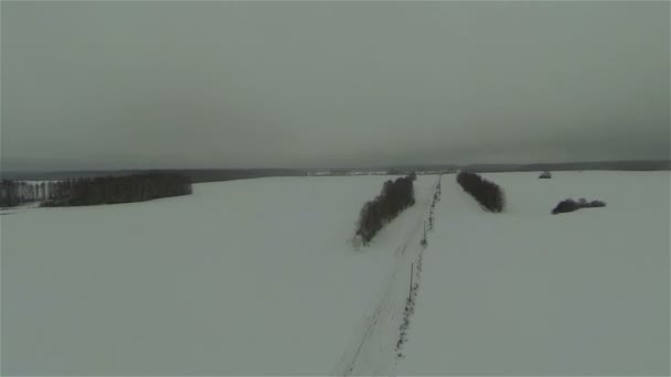 ロシアの国側、冬の雪のフィールドと道路の航空写真 — ストック動画