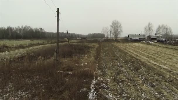 Vue aérienne des champs labourés, ferme d'automne, début de l'hiver, première neige, route de campagne avec piliers gris 