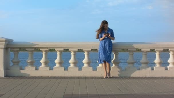 Menina bonita em vestido azul usando tablet digital . — Vídeo de Stock