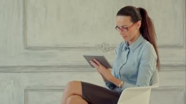 Dijital tabletli iş kadını. Dijital tablet üzerinde çalışan ve gülümseyen kendinden emin genç iş kadını