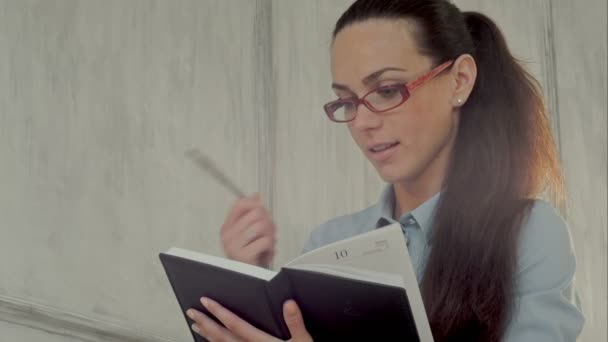 Mujer de negocios sonriente en gafas con bloc de notas — Vídeo de stock