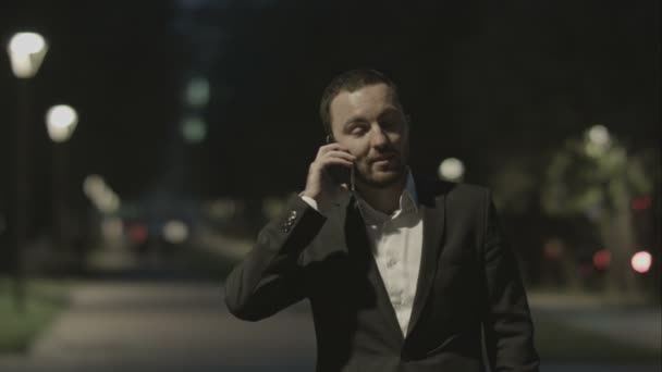 Zakenman vriendelijk praten via de telefoon in het stadspark in goed humeur. — Stockvideo