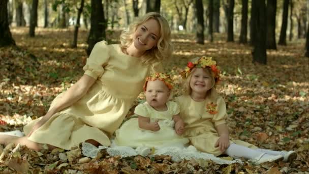 Jeune mère avec des feuilles d'érable assise avec des enfants — Video