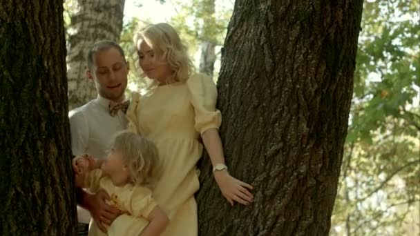 森の背景の上にキス彼女の小さな娘と幸せなカップル — ストック動画