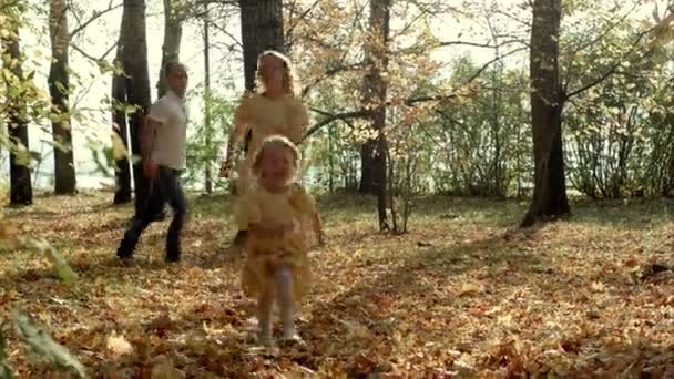 Chica feliz corriendo por delante de sus padres en el parque de otoño — Vídeo de stock