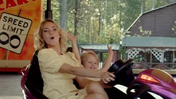 Happy mother with her daughter drive on bumper cars in Amusement park — Stock Video