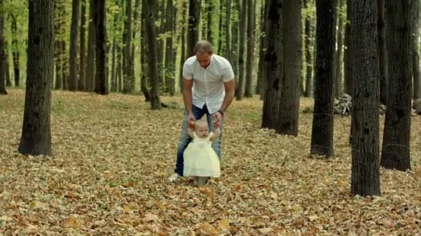 Papà e il suo bambino fanno il primo passo nel parco autunnale — Video Stock