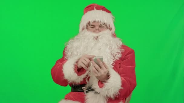 Santa claus να διαβάζει και να στέλνει μηνύματα κειμένου από το τηλέφωνο κυττάρων σε ένα πράσινο οθόνη Chrome κλειδί — Αρχείο Βίντεο