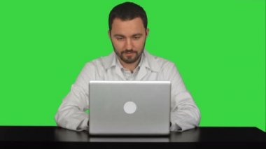 Yeşil Ekranda dizüstü bilgisayar ile masada oturan gülümseyen erkek doktor, Chroma Key