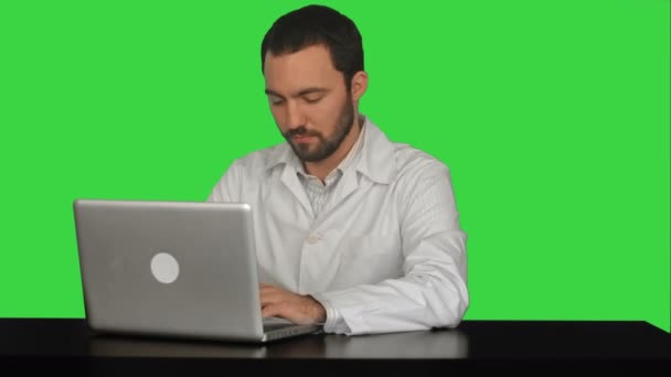 Joven médico pensando idea con ordenador portátil sobre la mesa en una pantalla verde, Chroma Key — Vídeos de Stock